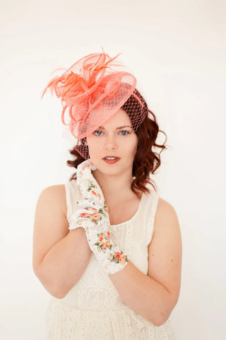 Coral pink fascinator with feathers on headband, ideal for weddings, races, and special occasions